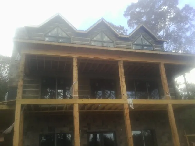 Dormers and porch framing on a large log home under construction — Roof Coating work by our crew in Cokeburg