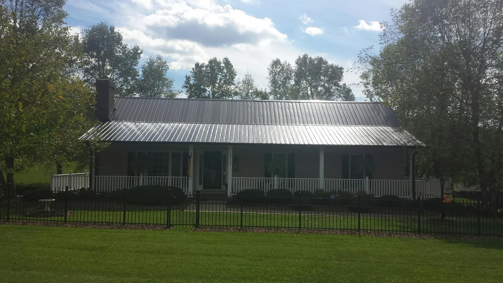 Gray metal roof on a brick ranch with a full width front porch — Gutter Guard Installation work by our crew in Cokeburg