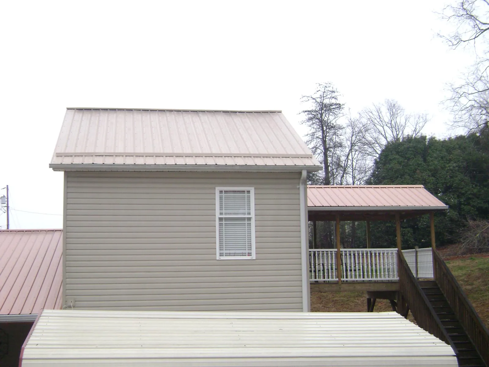 Tan metal roofs on a two story addition and attached porch, from a Roof Replacement job in Cokeburg