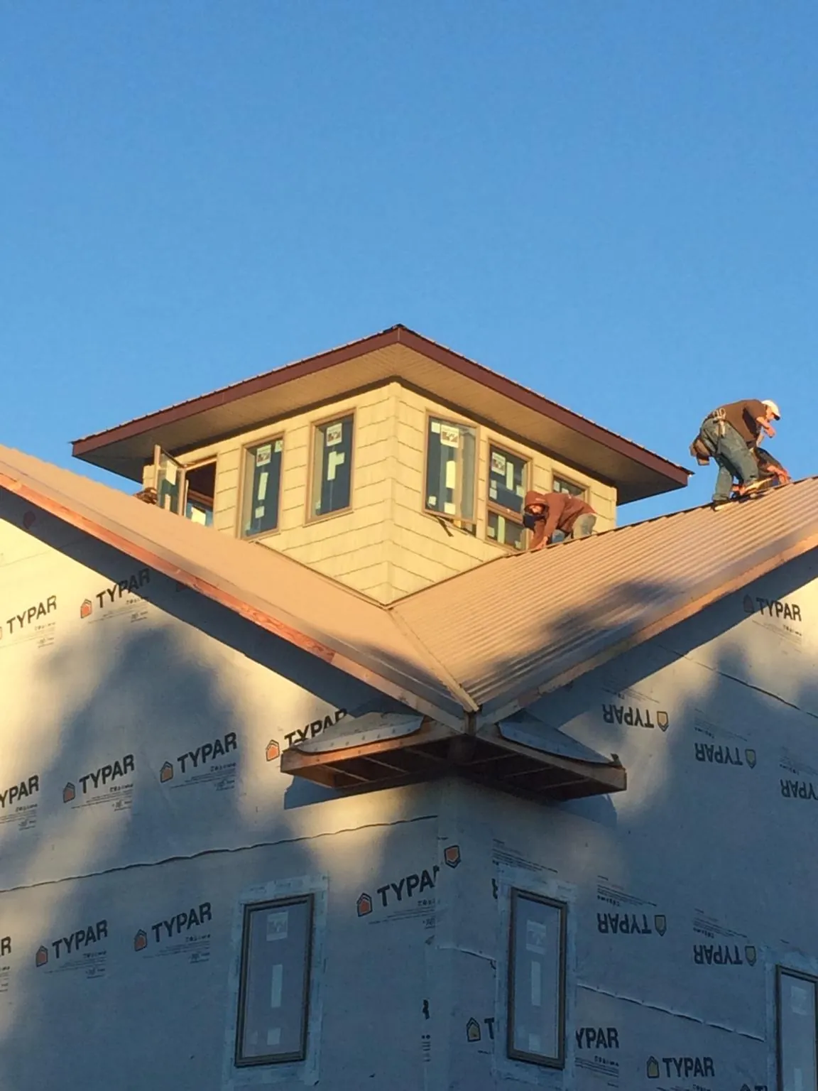 Roofers working around a rooftop cupola on a new metal roof at sunset — Roof Waterproofing in Cokeburg by Roofing Brothers